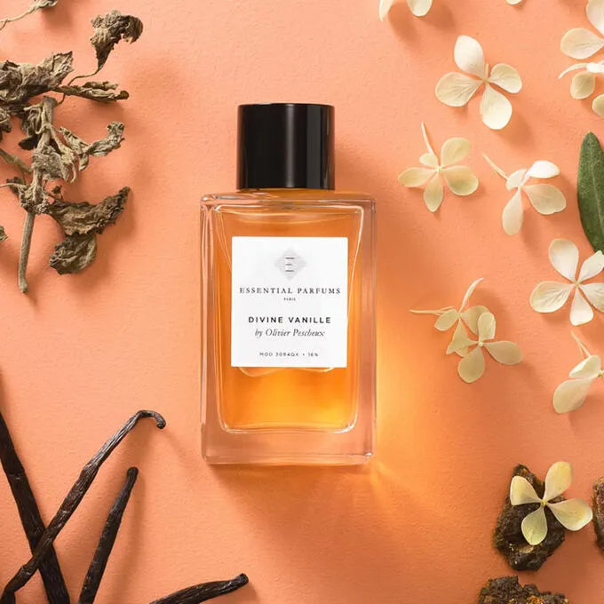 Perfume bottle labeled 'Divine Vanille' by Essential Parfums on a peach background with vanilla beans and flowers.