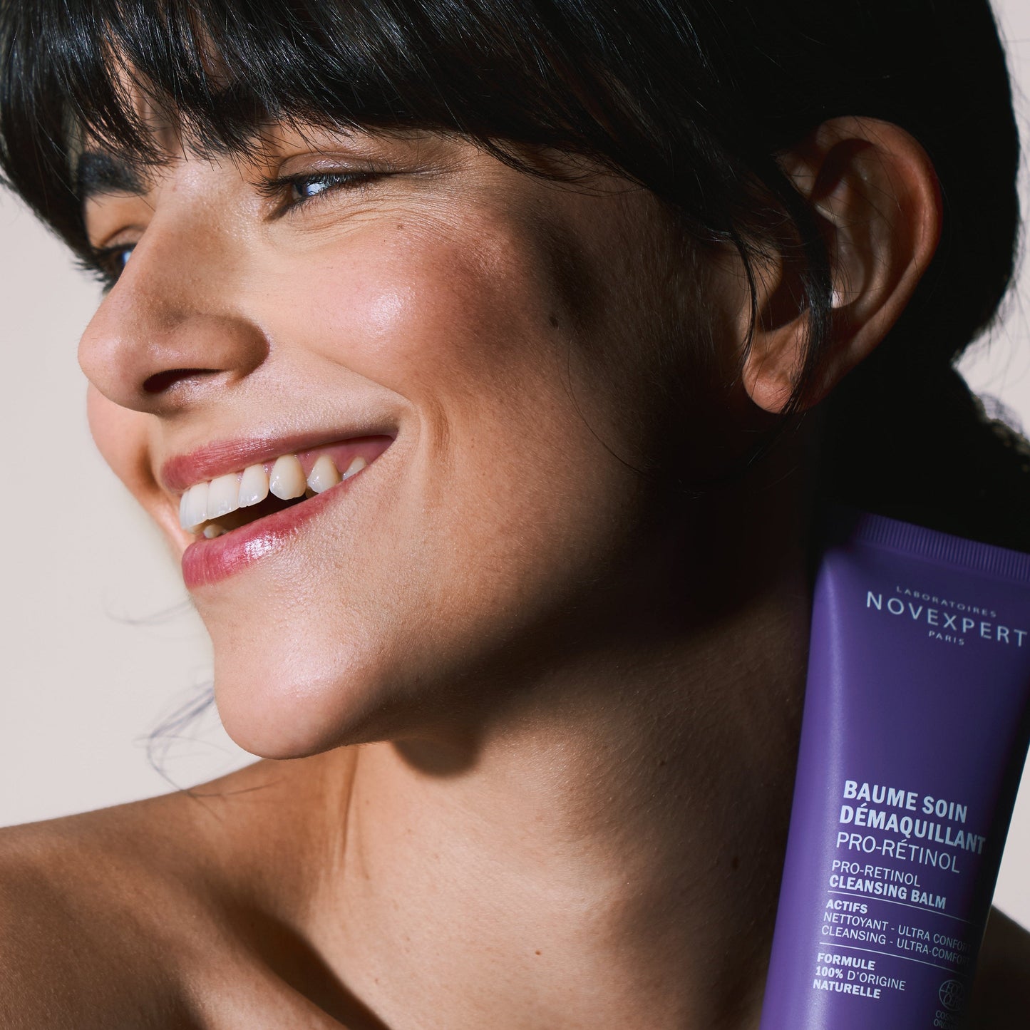 Woman holding a purple skincare product with 'NOVEFFECT' branding.