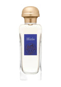 A clear glass perfume bottle with a metallic gold cap and a blue label reading 'Hiris' on a light gray background.