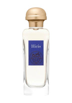 A clear glass perfume bottle with a metallic gold cap and a blue label reading 'Hiris' on a light gray background.
