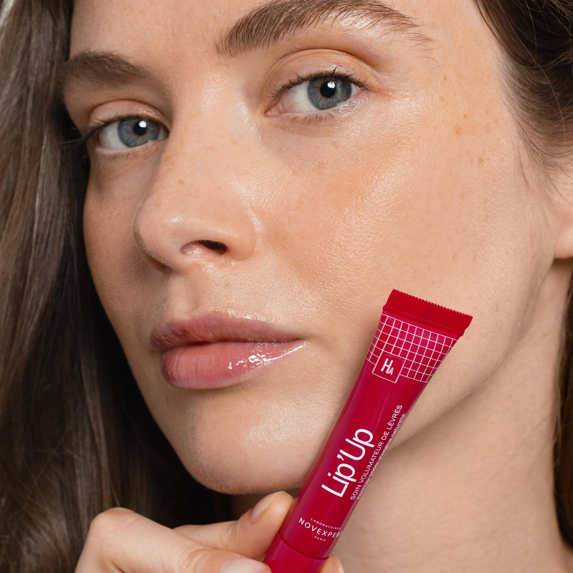 Woman holding a red 'Lip Up' product close to her face