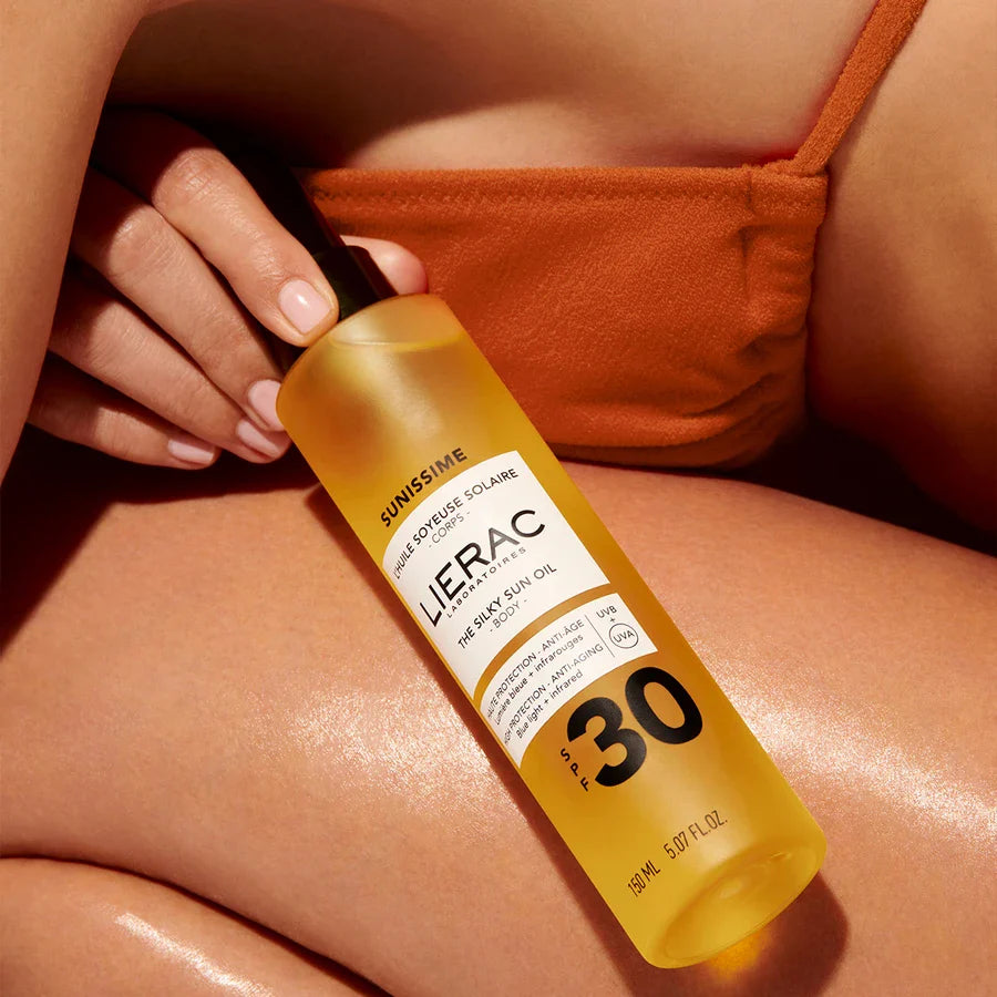 Lierac sun oil bottle held by a person with sun-kissed skin
